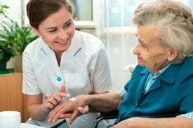 Caregiver assisting elderly woman with health monitoring